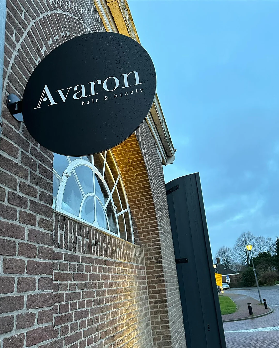 Het ronde Avaron-bord aan de bakstenen gevel, met het waaiervenster eronder